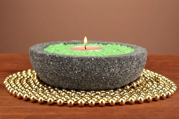 Świeca kamień miski z soli morskiej, na drewnianym stole, na brązowym tle — Zdjęcie stockowe