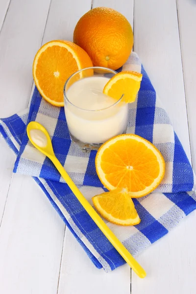 Вкусный йогурт в стакане с апельсином на деревянном столе крупным планом — стоковое фото