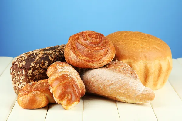 Composition with bread and rolls on wooden table, on color background — Stock Photo, Image