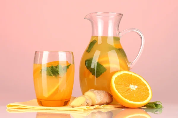 Limonata arancione in brocca e vetro su fondo rosa — Foto Stock