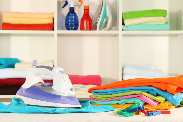 Одежда и утюг на столе на полках
