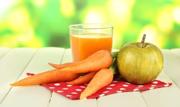 Un mucchio di carote e mela verde, vetro di succo, su tavolo di legno a colori su sfondo brillante — Foto Stock