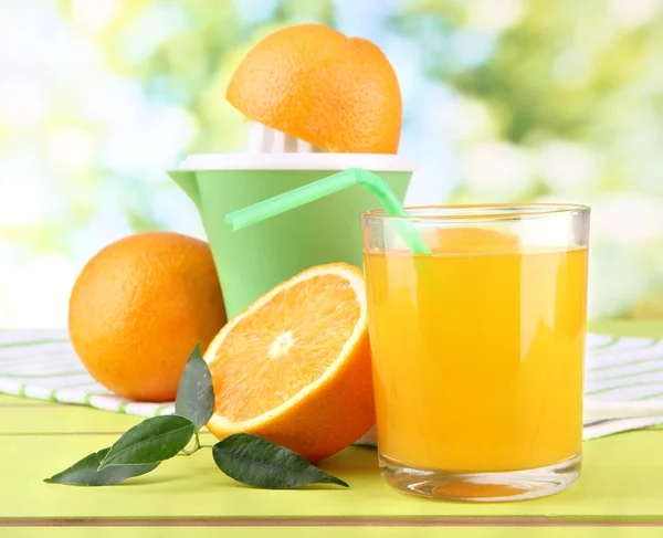 Citrus press, glass of juice and ripe oranges on white wooden table — Stock Photo, Image