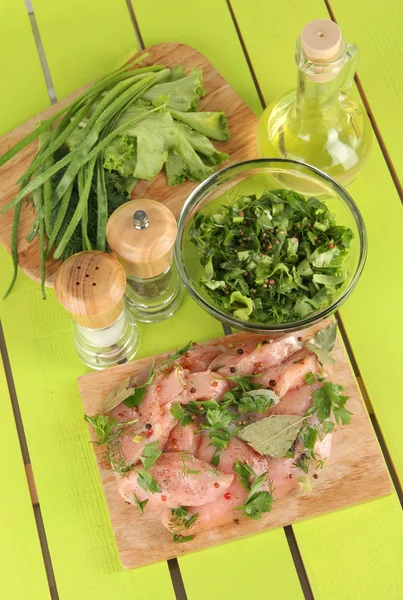 Carne de frango em placa de vidro, ervas e especiarias em mesa de madeira — Fotografia de Stock