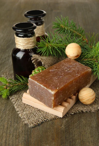 Hand-made soap and bottles of fir tree oil on wooden background — Stock Photo, Image