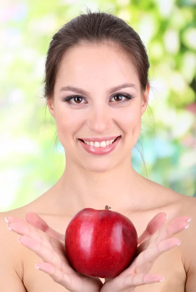 Улыбающаяся женщина с яблоком на ярком фоне — стоковое фото