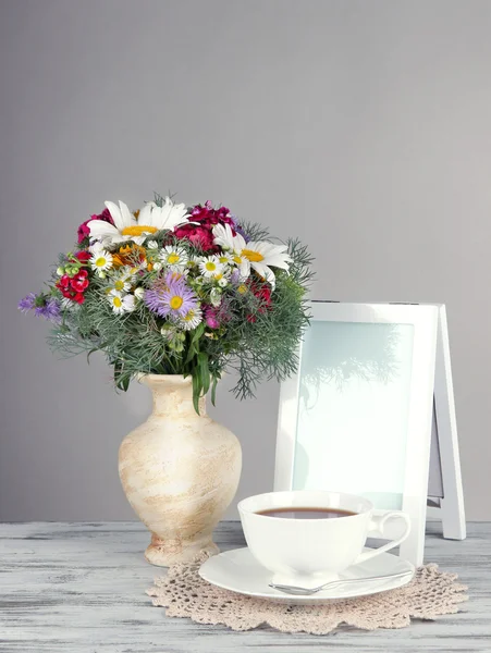 Beautiful bright flowers in vase on table on gray background — Stock Photo, Image