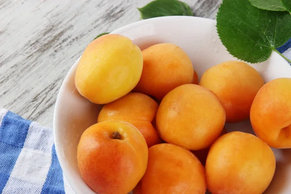 Apricots on board for cutting on napkin on wooden table — Stock Photo, Image