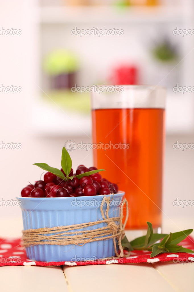 Glass of cranberry juice and ripe red cranberries in bowl on table