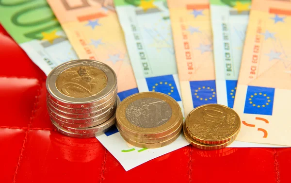 Euro banknotes and euro cents on red background — Stock Photo, Image