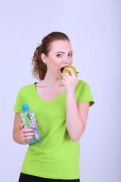 Schöne junge Frau mit Flasche Wasser und Apfel — Stockfoto
