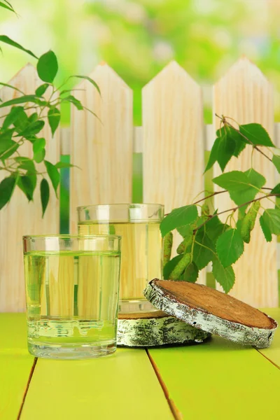 Glasses of birch sap on green wooden table — Stock Photo, Image