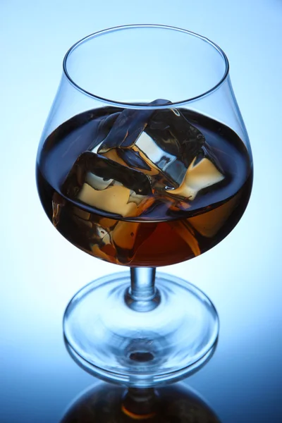 Bicchiere di brandy con ghiaccio su sfondo blu — Foto Stock