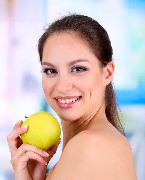 Mujer sonriente con manzana sobre fondo brillante — Foto de Stock