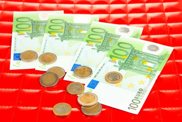 Banconote in euro e centesimi di euro su sfondo rosso — Foto Stock
