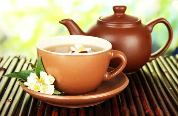 Xícara de chá com jasmim, no tapete de bambu, no fundo brilhante — Fotografia de Stock