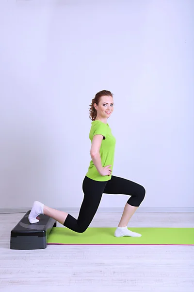 Mooie jonge vrouw oefeningen op stepper — Stockfoto