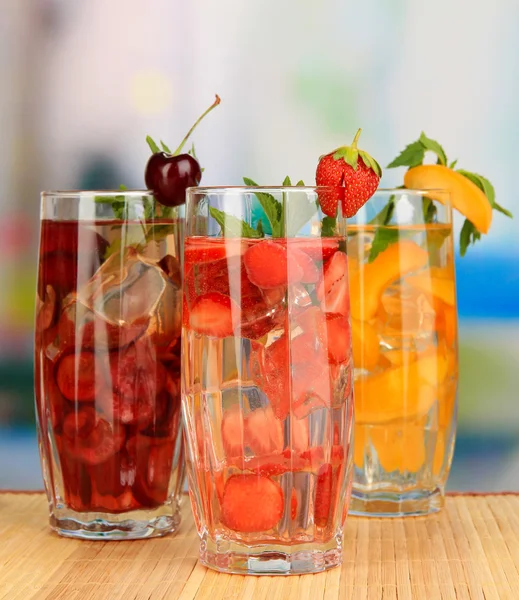 Glasses of fruit drinks with ice cubes on table in cafe — Stock Photo, Image