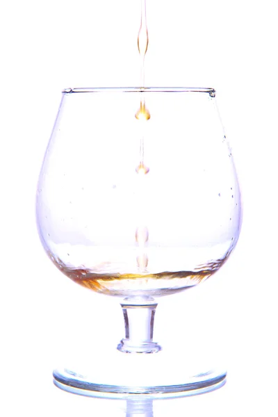 Brandy derramando em vidro isolado em branco — Fotografia de Stock