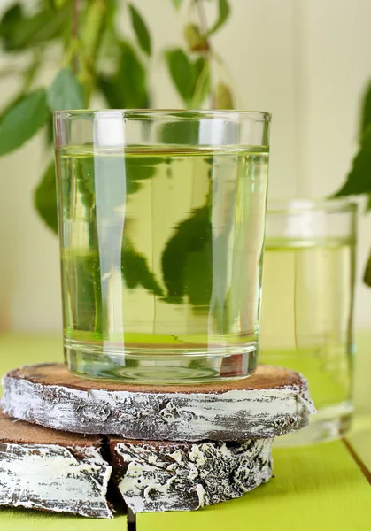 Glasses of birch sap on green wooden table — Stock Photo, Image