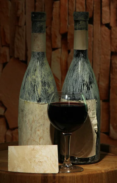 Composition with old bottle of wine and wineglass in old cellar, on dark background