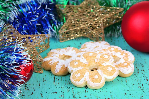 Weihnachtsplätzchen und Dekorationen auf farbigem Holzhintergrund — Stockfoto