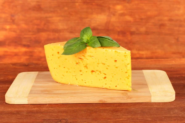 チーズとバジルの木製の背景にカッティング ボード — ストック写真