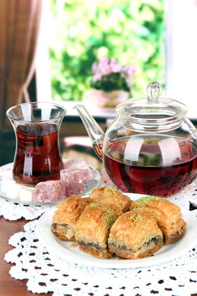 Sweet baklava on plate with tea on table in room — Stock Photo, Image