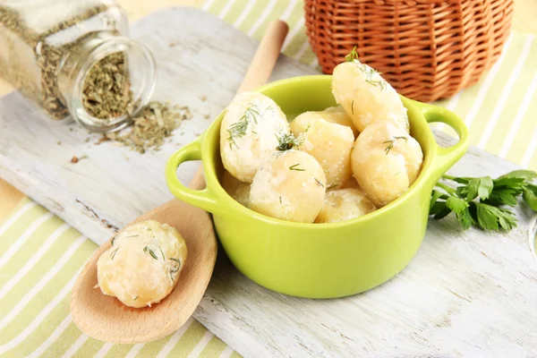 Tender young potatoes with sour cream and herbs in pan on wooden board on table close-up — Stock Photo, Image