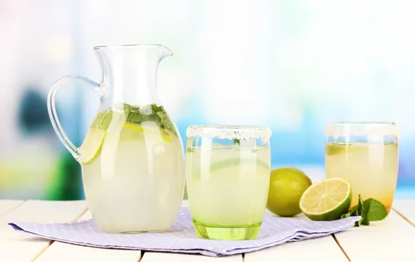 Citronnade d'agrumes en pichet et verres sur table en bois sur fond de pièce — Photo