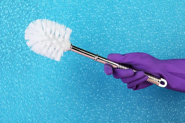 Toilet brush in hand on blue background — Stock Photo, Image