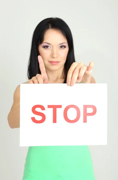 Mädchen zeigt Stoppschild auf grauem Hintergrund — Stockfoto