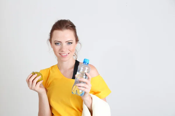 Vacker ung kvinna med en flaska vatten och äpple — Stockfoto