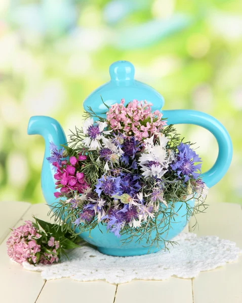 Beautiful bouquet in blue teapot on wooden table on natural background — Stock Photo, Image