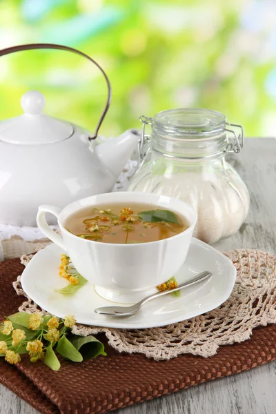 Kopje thee met linden op servetten op houten tafel op aard achtergrond — Stockfoto