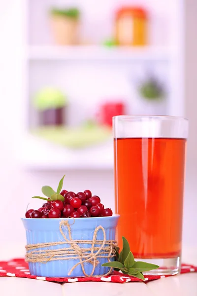 Glass of cranberry juice and ripe red cranberries in bowl on table — Stock Photo, Image
