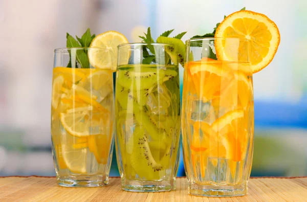 Glasses of fruit drinks with ice cubes on table in cafe — Stock Photo, Image