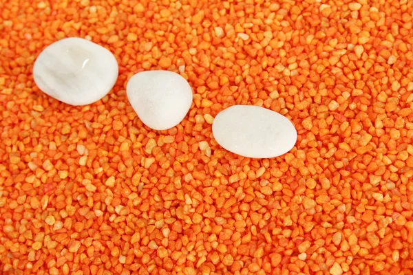 White stones on orange crystals of sea salt background — Stock Photo, Image