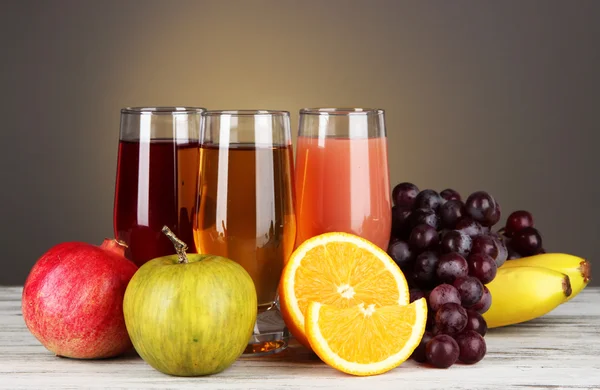 Glasögon av färsk juice på bordet på grå bakgrund — Stockfoto