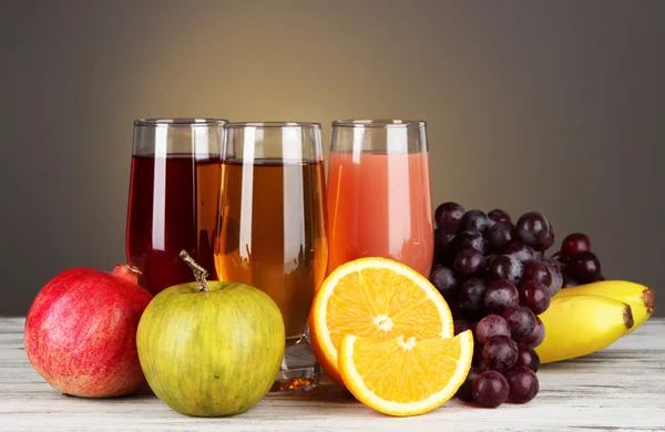 Vasos de jugo fresco en la mesa sobre fondo gris —  Fotos de Stock