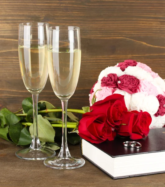 Anneaux de mariage sur bible avec des roses et des verres de champagne sur fond en bois — Photo