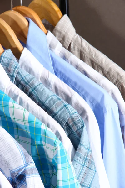 Men's shirts on hangers on gray background