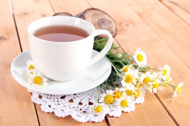 bardak papatya çayı ve ahşap masa üzerinde papatya