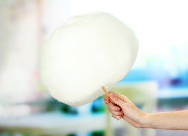 Pamuk şeker, sopayla parlak arka planda tutan el