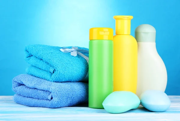 Cosmétiques pour bébés, serviettes et savon sur table en bois, sur fond bleu — Photo