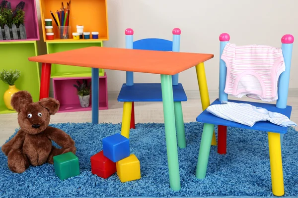 Kleine en kleurrijke tafel en stoelen met kleren van de baby — Stockfoto