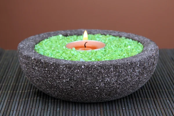 Candle in stone bowl with marine salt, on bamboo mat, on brown background — Stock Photo, Image