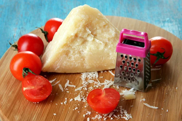 Pedaço de queijo parmesão em tábua de madeira em mesa azul close-up — Fotografia de Stock
