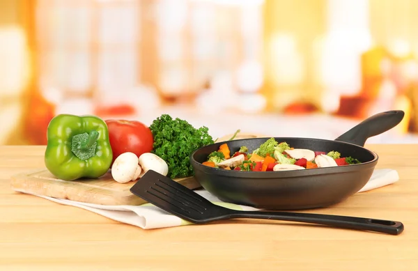 Ragú vegetal en sartén, sobre mesa de madera sobre fondo brillante — Foto de Stock