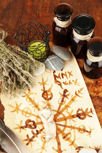 Composition with old papers, herbs, stones and bottles with symbols on wooden background — Stock Photo, Image